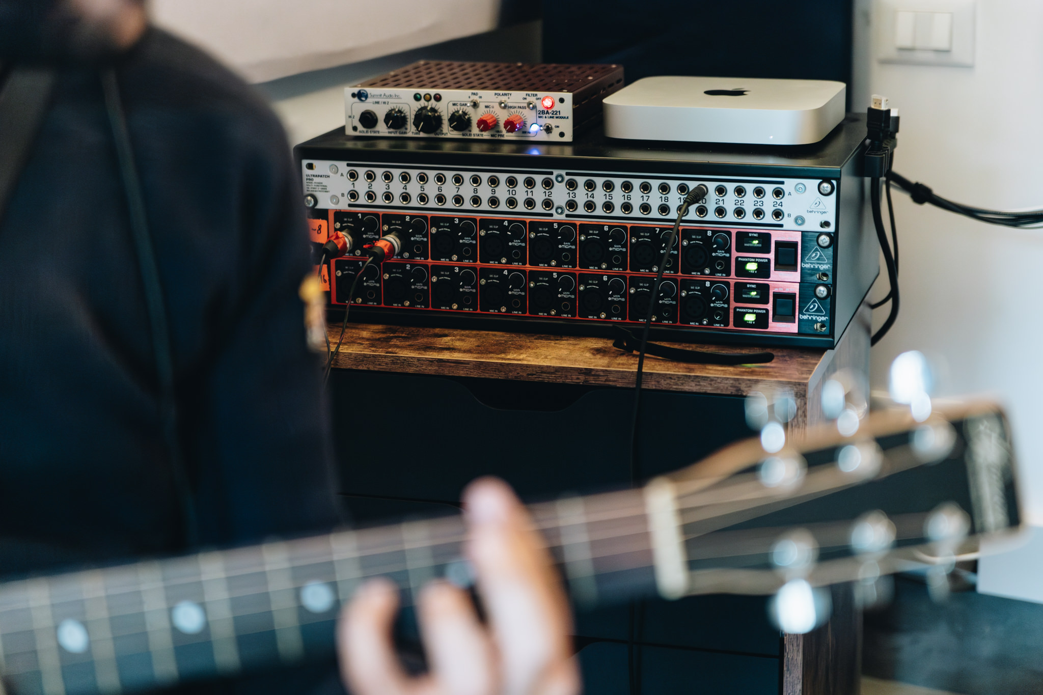 Chitarra elettrica in primo piano e rack di outboard in regia