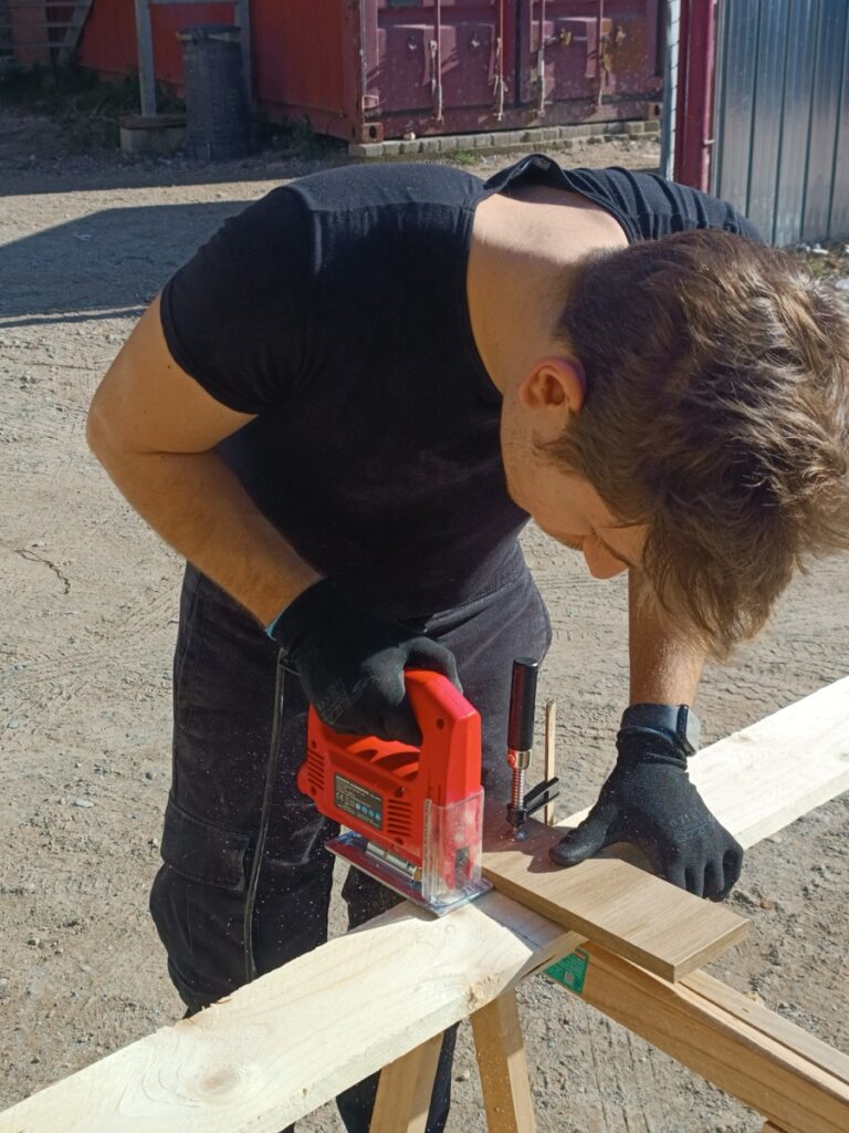Taglio di una tavola di legno con il seghetto alternativo, all’aperto
